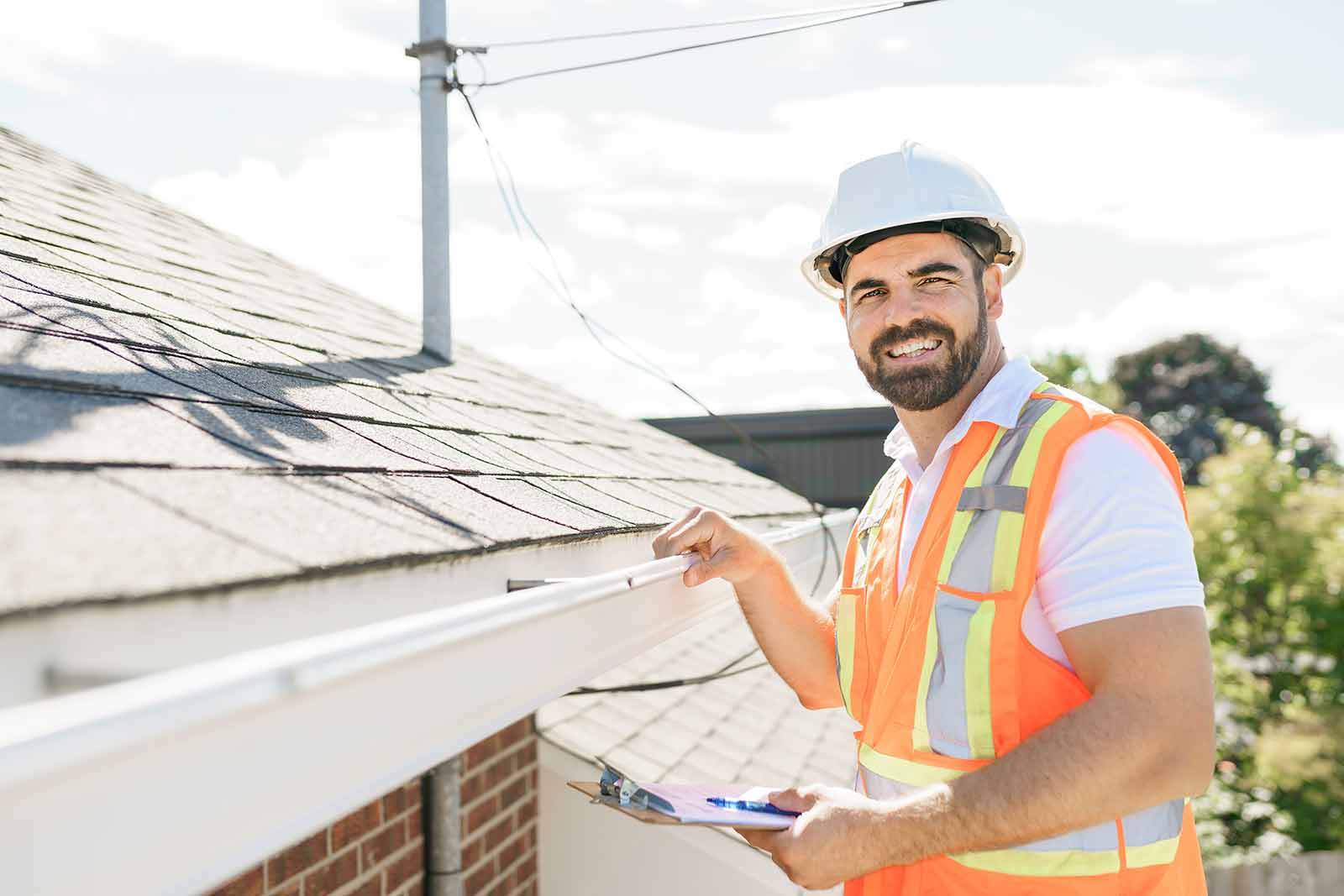 professional roofer inspecting a home’s roof and gutters during a roof inspection.